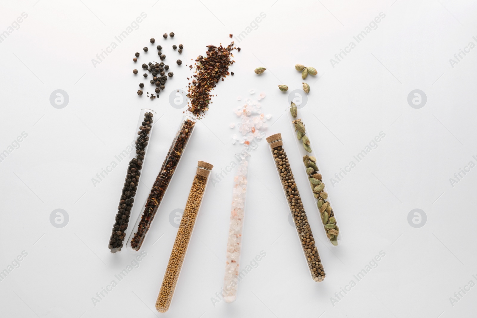 Photo of Glass tubes with different spices on white background, flat lay