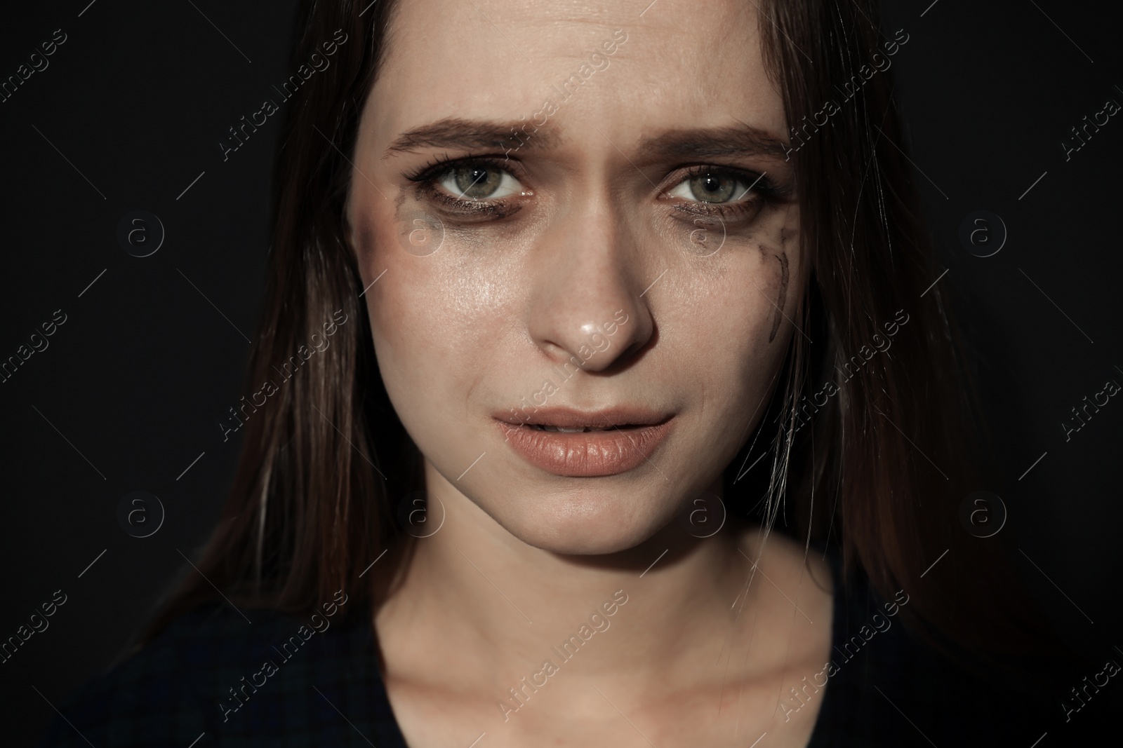 Photo of Crying young woman on dark background. Stop violence