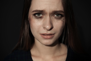 Crying young woman on dark background. Stop violence