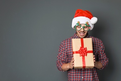 Photo of Young man with Christmas gift on grey background