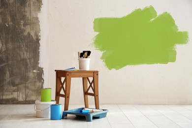 Image of Set with decorator's tools and paint on floor near white wall