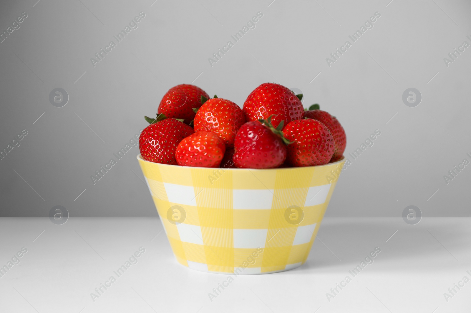 Photo of Fresh juicy strawberries in bowl on white table