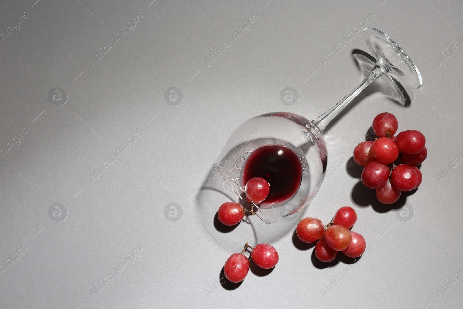 Photo of Overturned glass of wine and grapes on white background, flat lay. Space for text