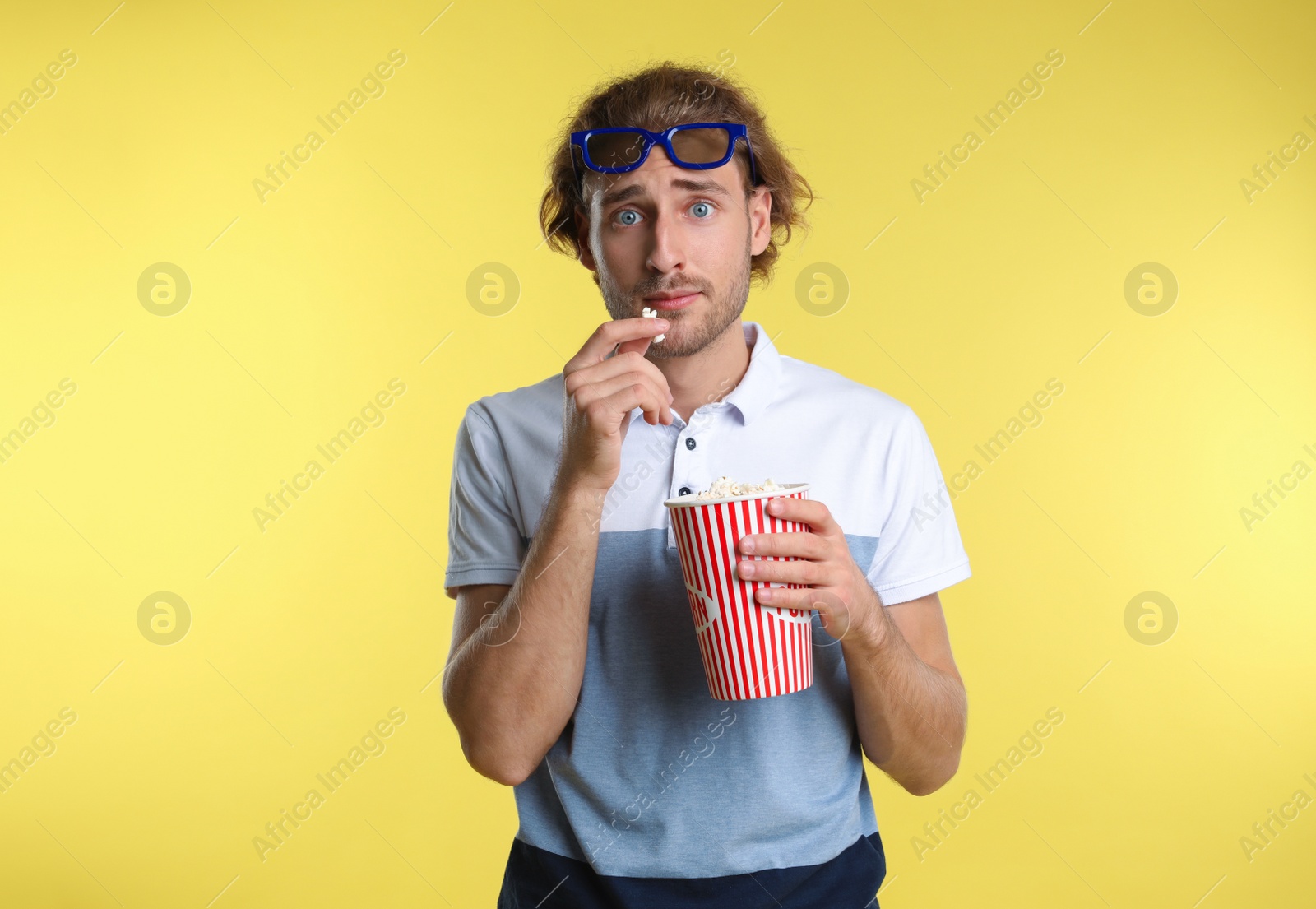 Photo of Emotional man with 3D glasses and popcorn during cinema show on color background