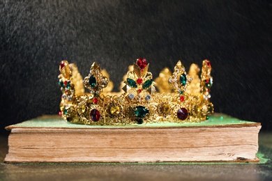 Photo of Beautiful golden crown on old book against black background. Fantasy item