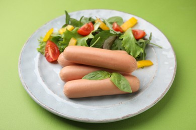 Photo of Delicious boiled sausages with salad on green