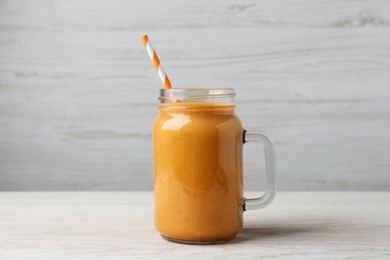 Mason jar with delicious fruit smoothie on white wooden table