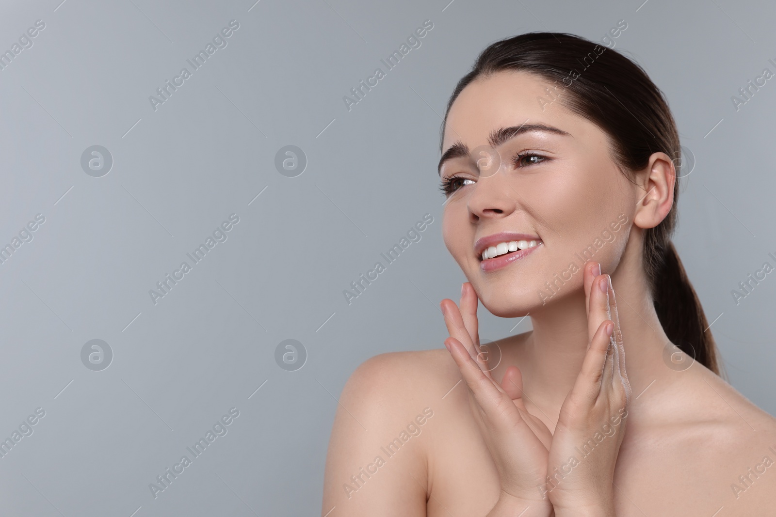 Photo of Young woman massaging her face on grey background. Space for text