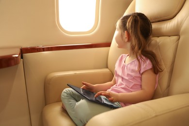 Photo of Cute little girl using tablet in airplane during flight