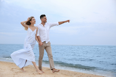 Happy couple having romantic walk on beach. Space for text