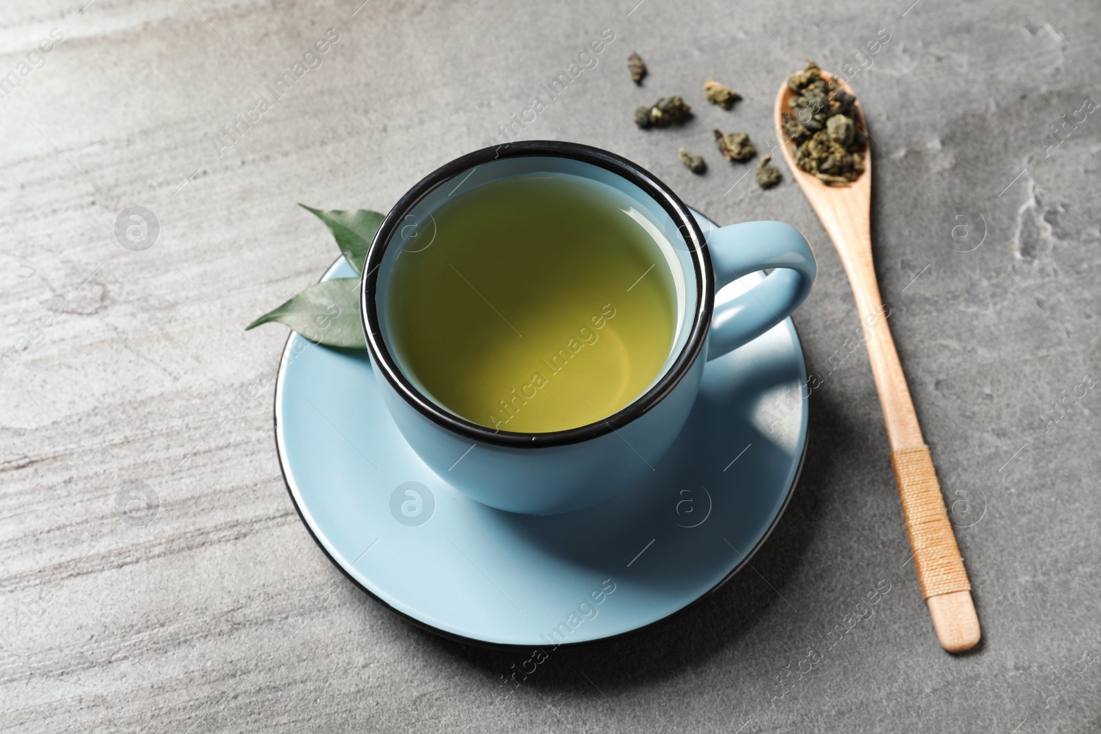 Photo of Cup of Tie Guan Yin oolong and spoon with tea leaves on table