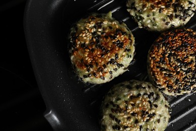 Cooking tasty vegan cutlets with sesame in grill pan on cooktop, top view