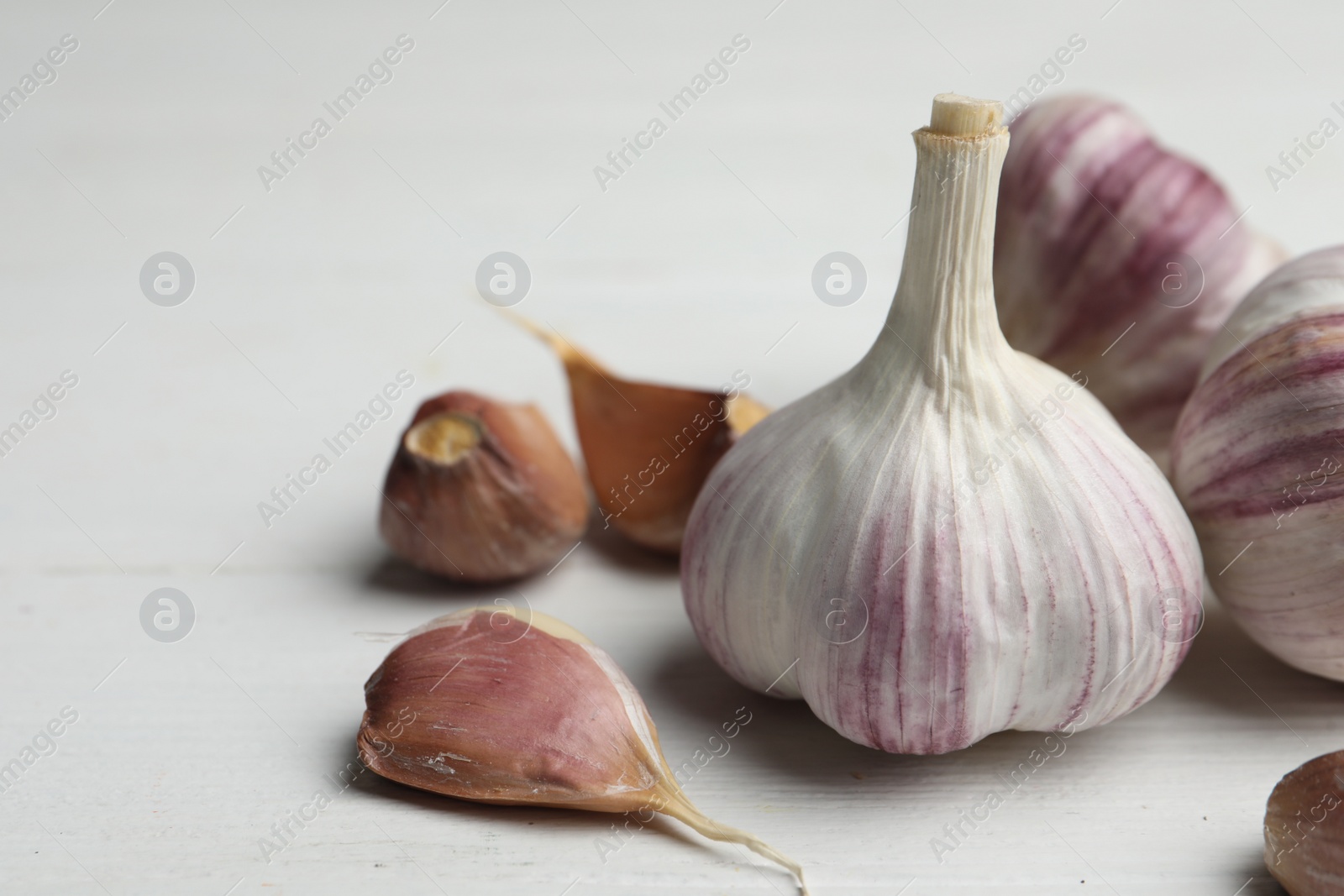 Photo of Fresh organic garlic on white wooden table, closeup