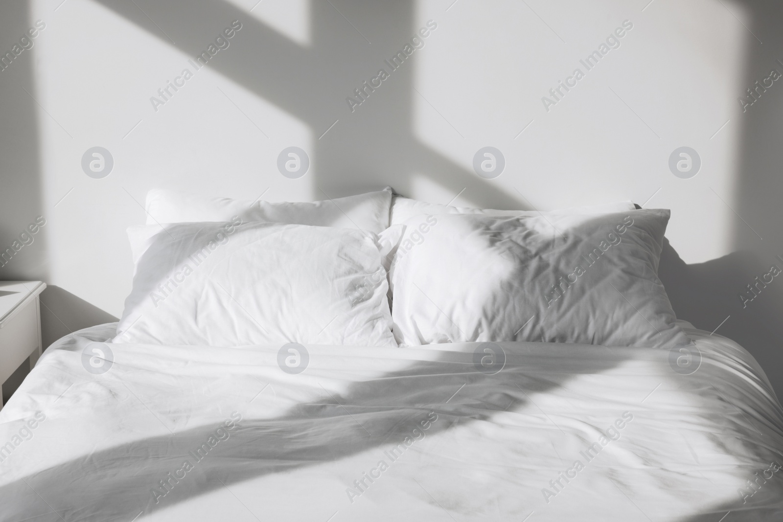 Photo of White soft pillows on bed in room