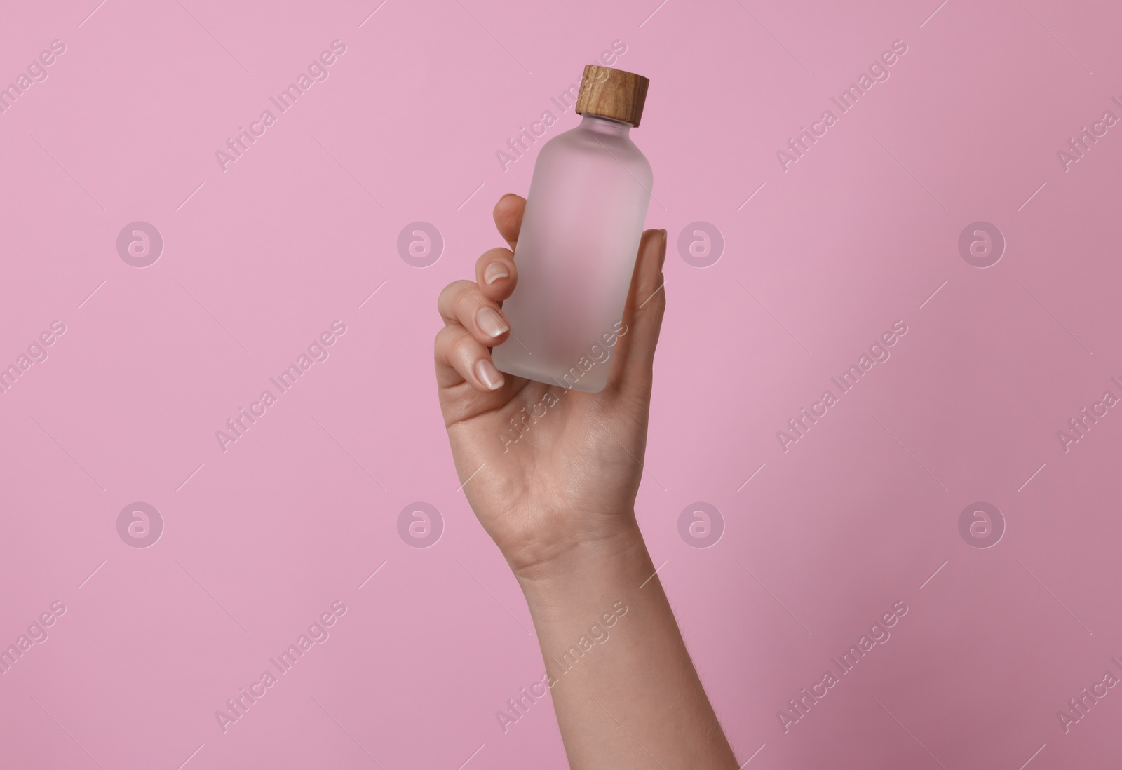 Photo of Woman holding bottle of cosmetic product on pink background, closeup
