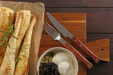 Tasty baked parsnips with rosemary served on wooden table, flat lay