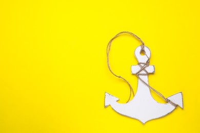 Photo of White wooden anchor figure on yellow background, top view. Space for text