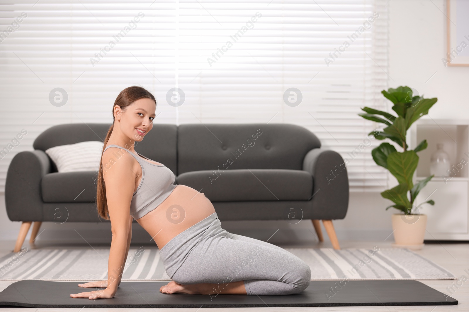 Photo of Pregnant woman doing exercises on yoga mat at home