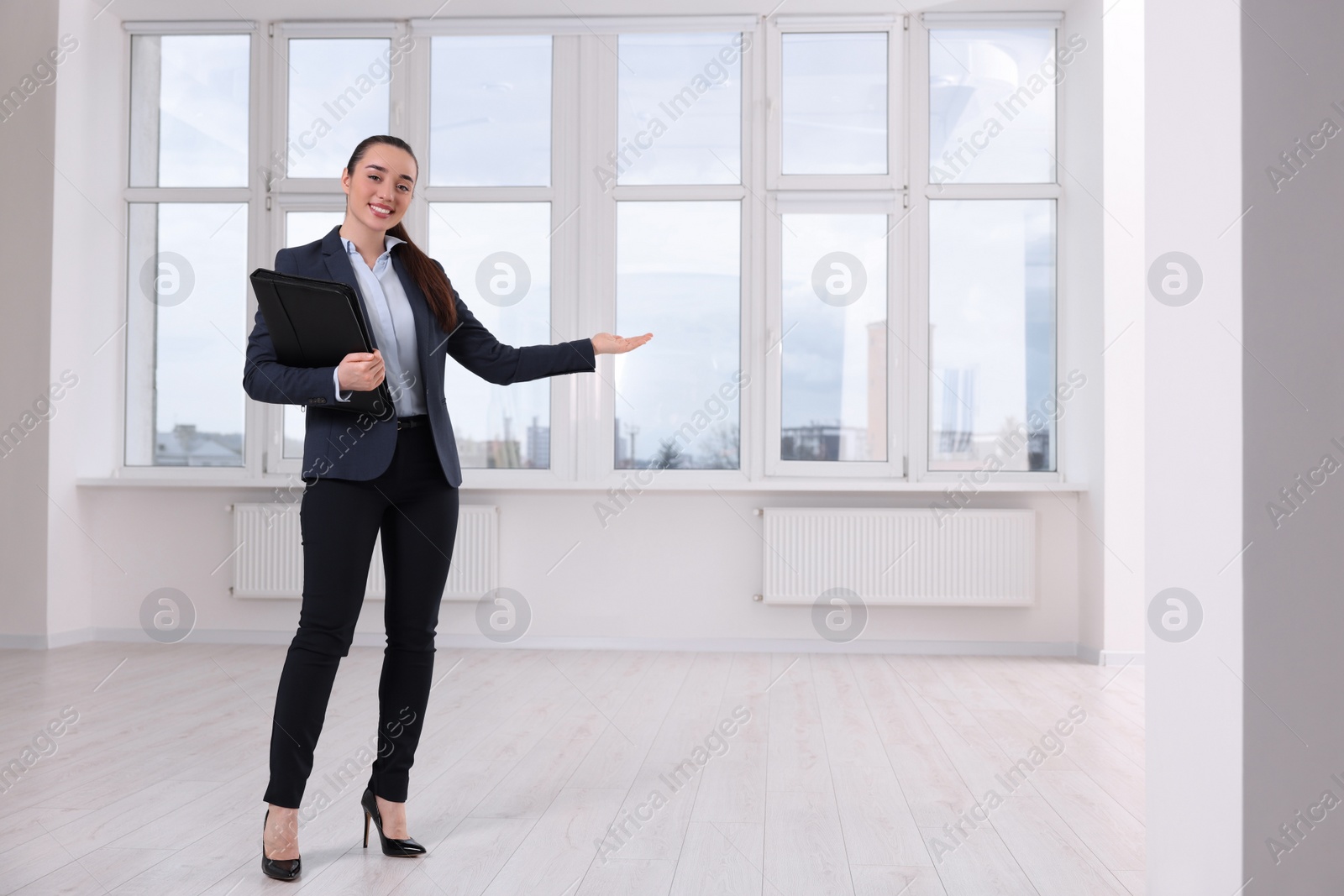 Photo of Happy real estate agent with leather portfolio showing new apartment