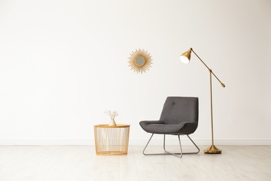 Photo of Stylish living room interior with comfortable chair and side table near white wall. Space for text