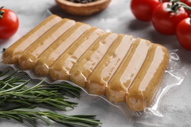 Photo of Vegan sausages and products on white marble table, closeup