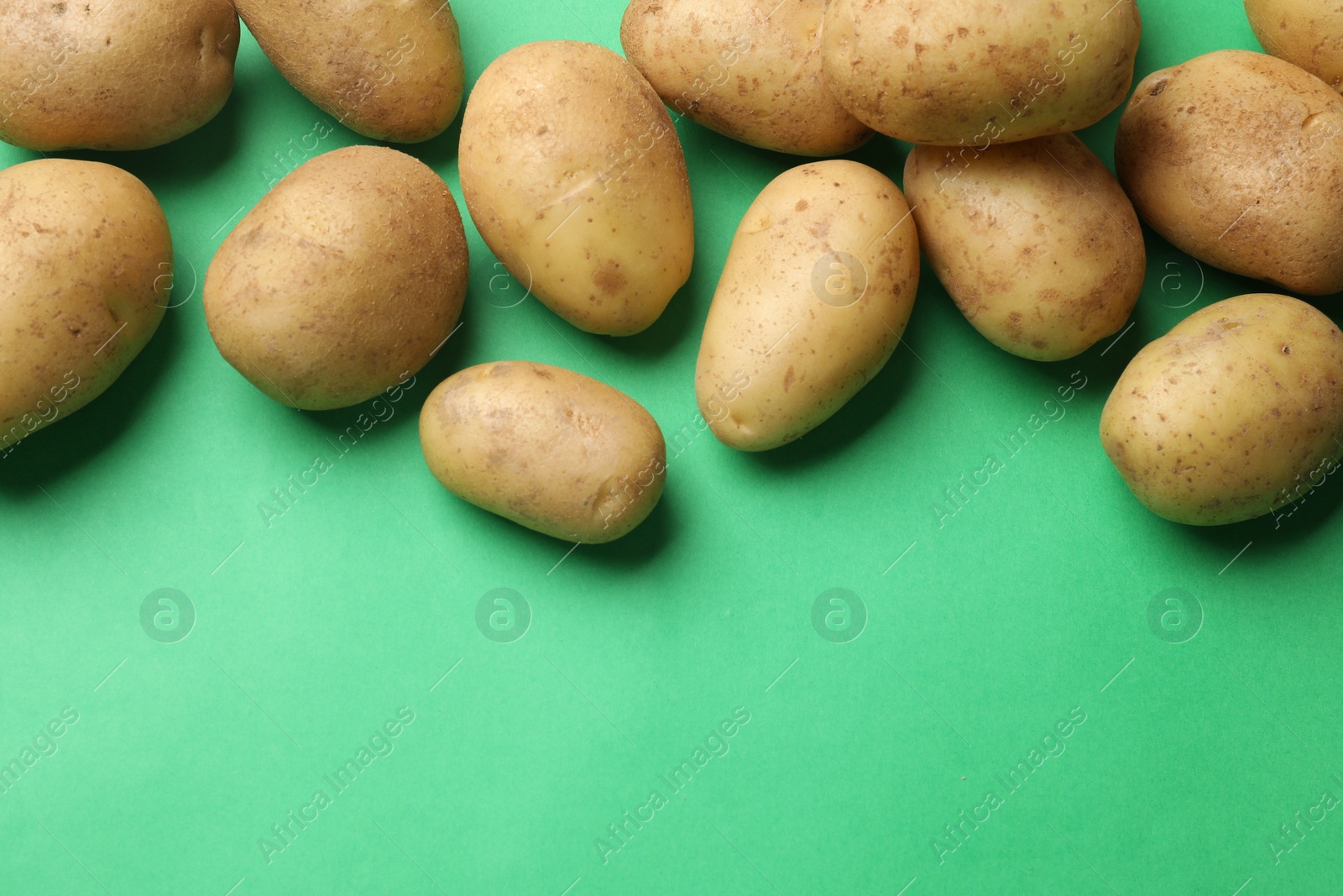 Photo of Fresh raw potatoes on green background, flat lay. Space for text