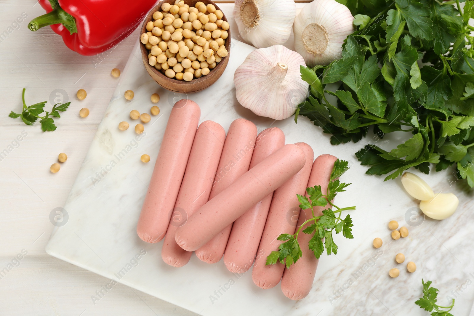 Photo of Fresh raw vegetarian sausages and vegetables on white wooden table, flat lay