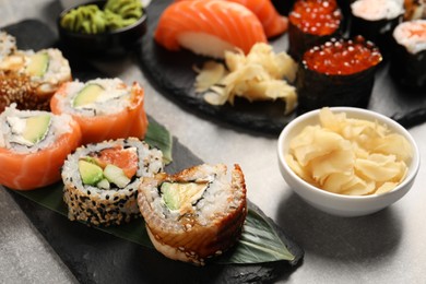 Photo of Delicious sushi rolls and ginger on light grey table, closeup