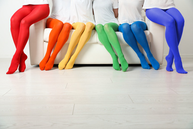 Women wearing colorful tights sitting on sofa indoors, closeup