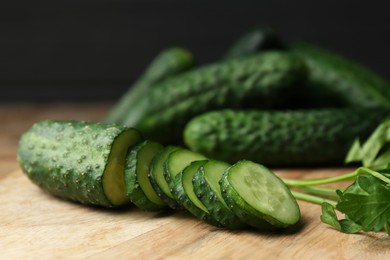 Photo of Fresh ripe cucumbers and parsley on wooden table, closeup