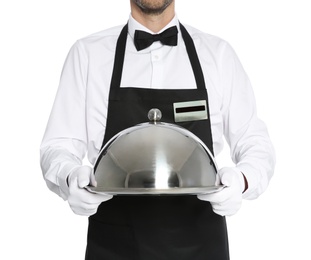 Young waiter holding metal tray with lid on white background