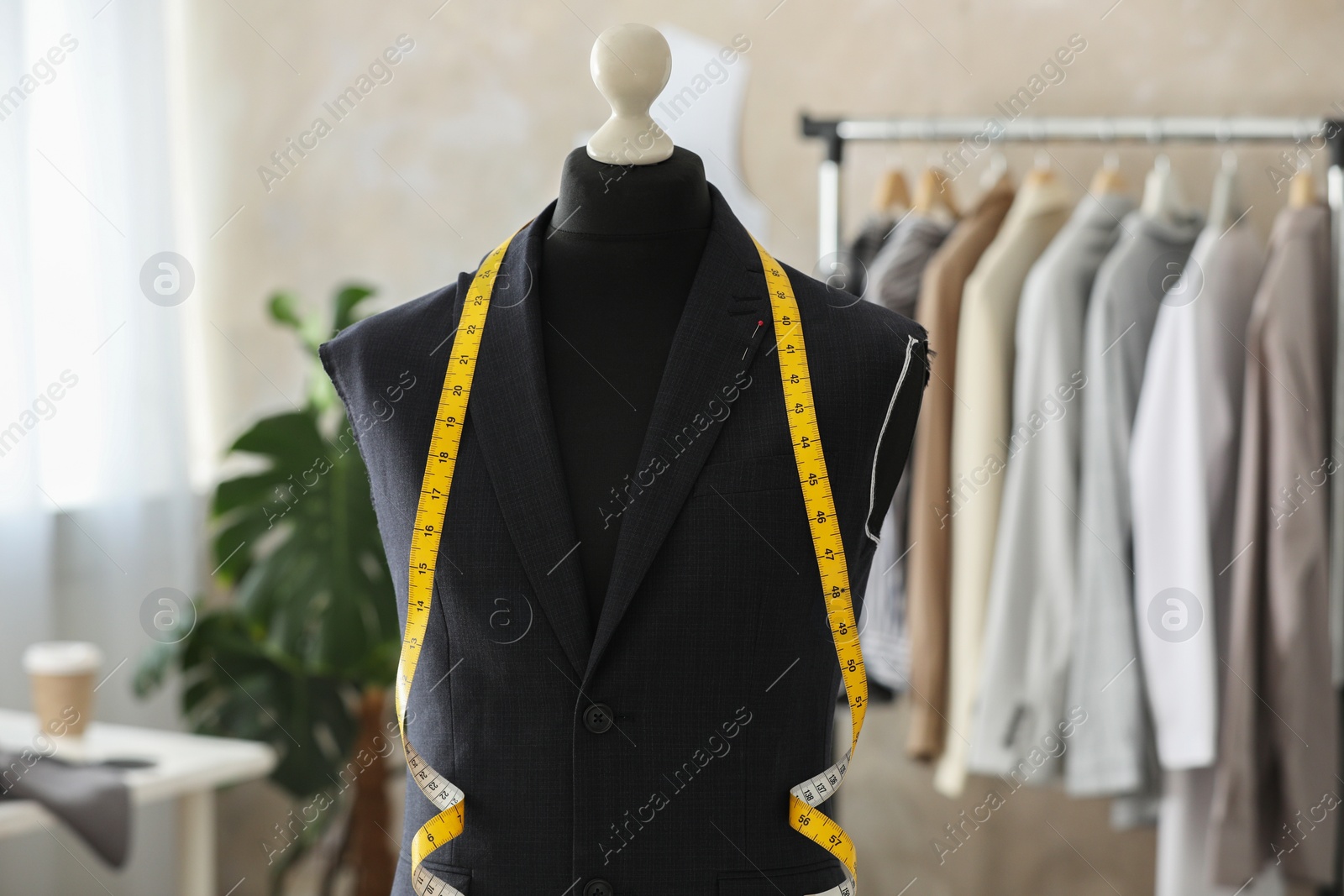 Photo of Mannequin with unfinished suit jacket and measuring tape in tailor shop