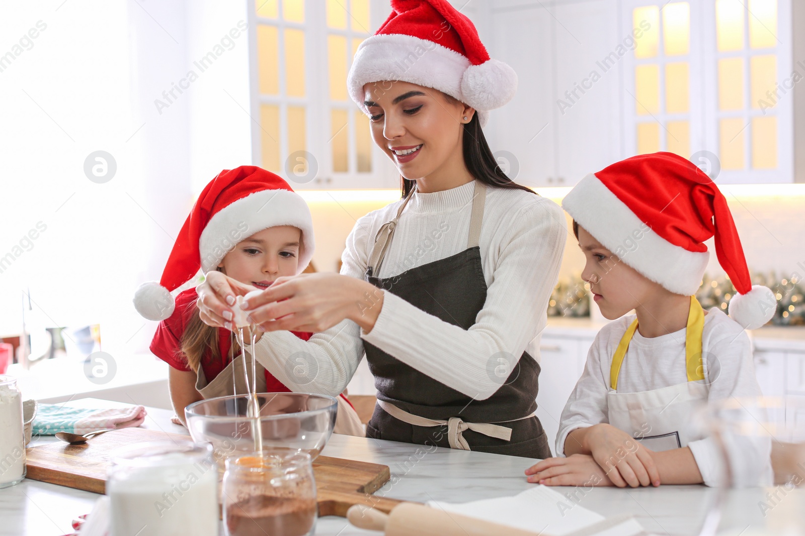 Photo of Mother with her cute little children making Christmas cookies in kitchen