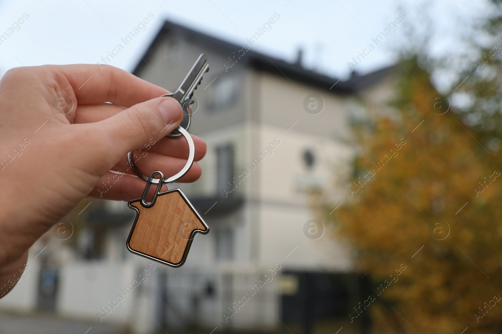 Photo of Woman holding house keys outdoors, closeup with space for text. Real estate agent