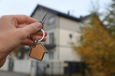 Woman holding house keys outdoors, closeup with space for text. Real estate agent