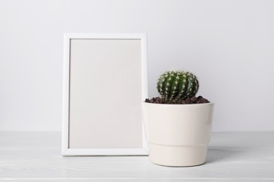 Cactus in pot and frame on white wooden table