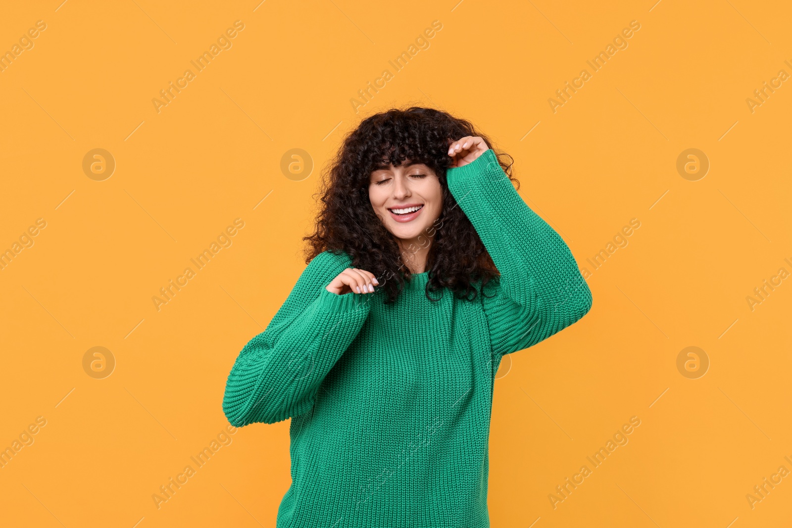 Photo of Happy young woman in stylish green sweater on yellow background