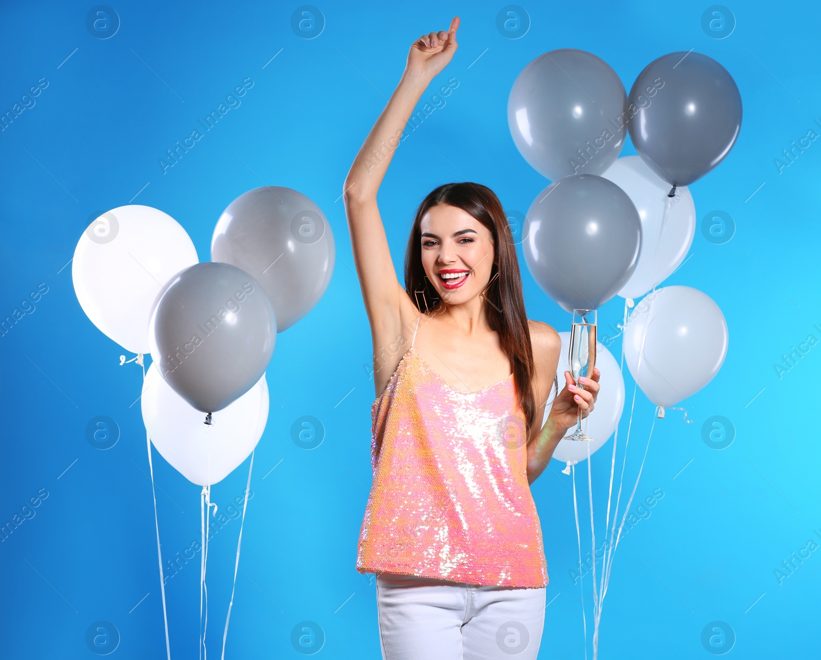 Photo of Portrait of happy woman with champagne in glass and party balloons on color background