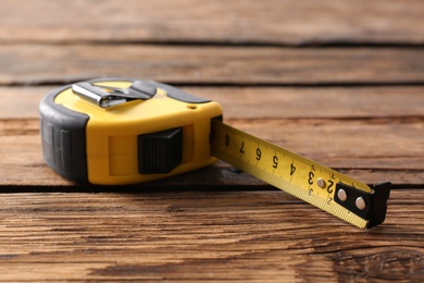 Metal measuring tape on wooden background. Construction tool