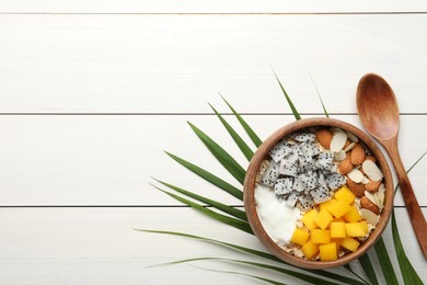 Bowl of granola with pitahaya, mango, almonds and yogurt on white wooden table, flat lay. Space for text