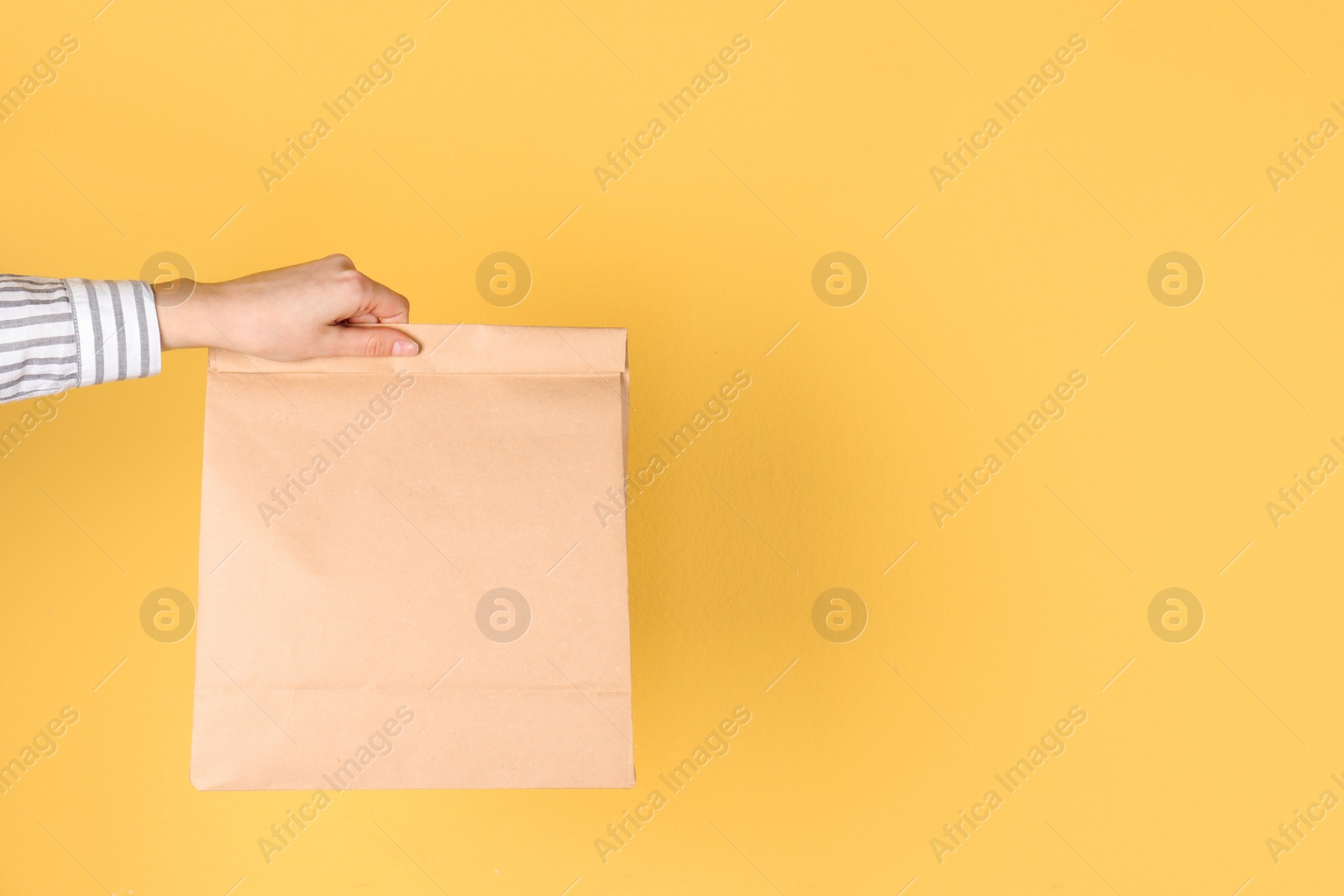 Photo of Woman holding paper bag on color background. Mockup for design