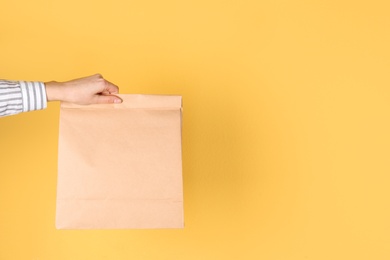 Woman holding paper bag on color background. Mockup for design