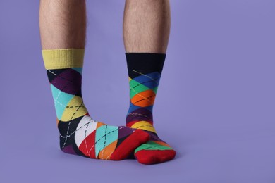 Photo of Man in different colorful socks on violet background, closeup. Space for text