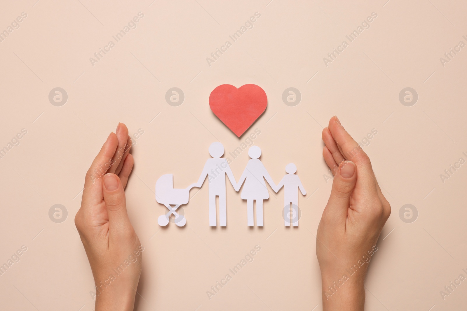 Photo of Woman protecting paper family figures and red heart on beige background, top view. Insurance concept