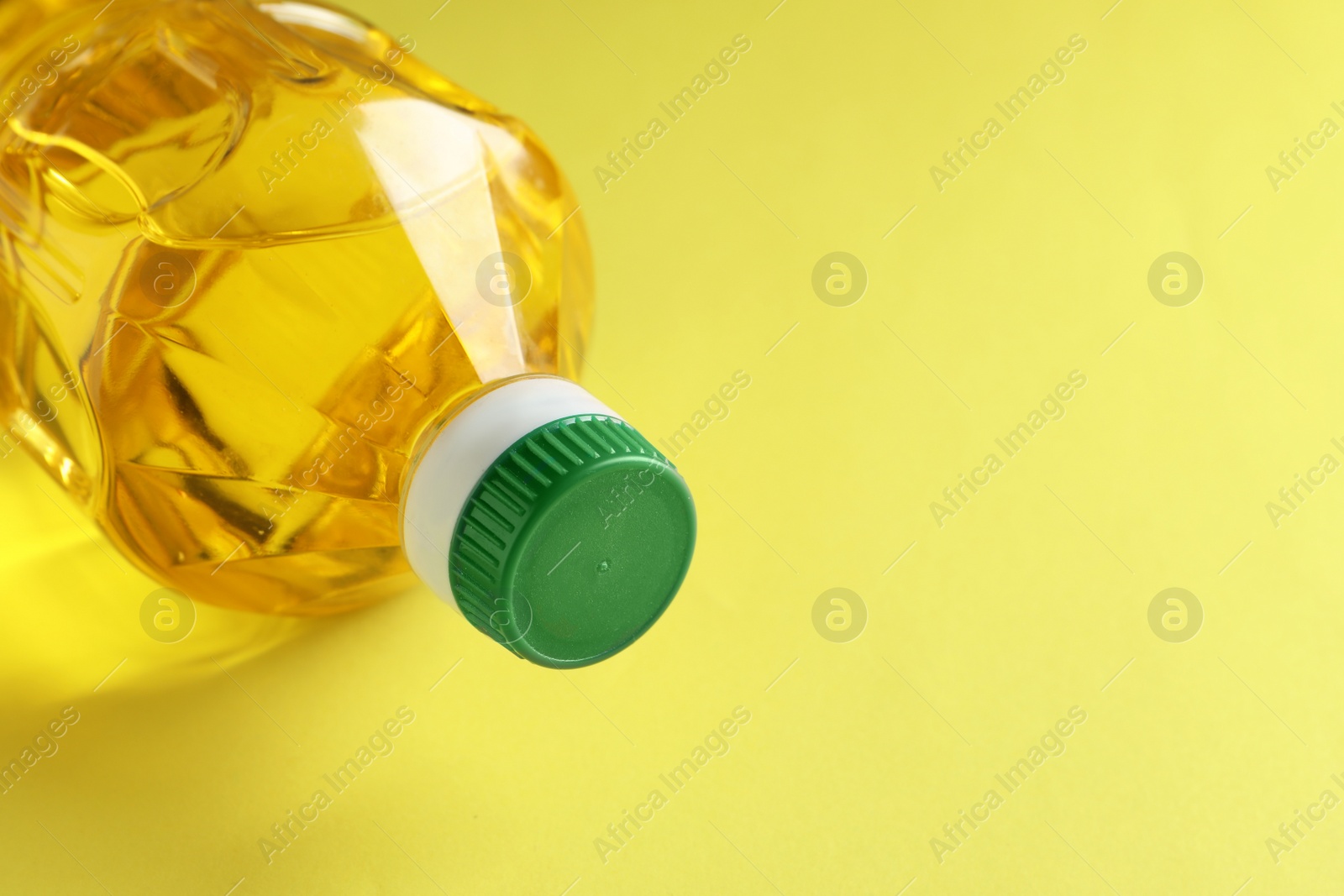 Photo of Plastic bottle of cooking oil on yellow background. Space for text