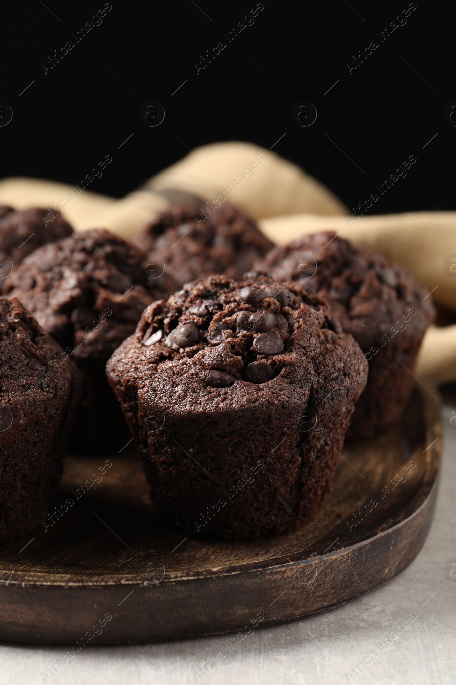 Photo of Board with delicious chocolate muffins on light table, closeup
