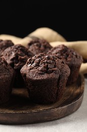 Board with delicious chocolate muffins on light table, closeup