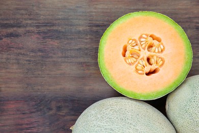Photo of Whole and cut fresh ripe melons on wooden table, flat lay. Space for text