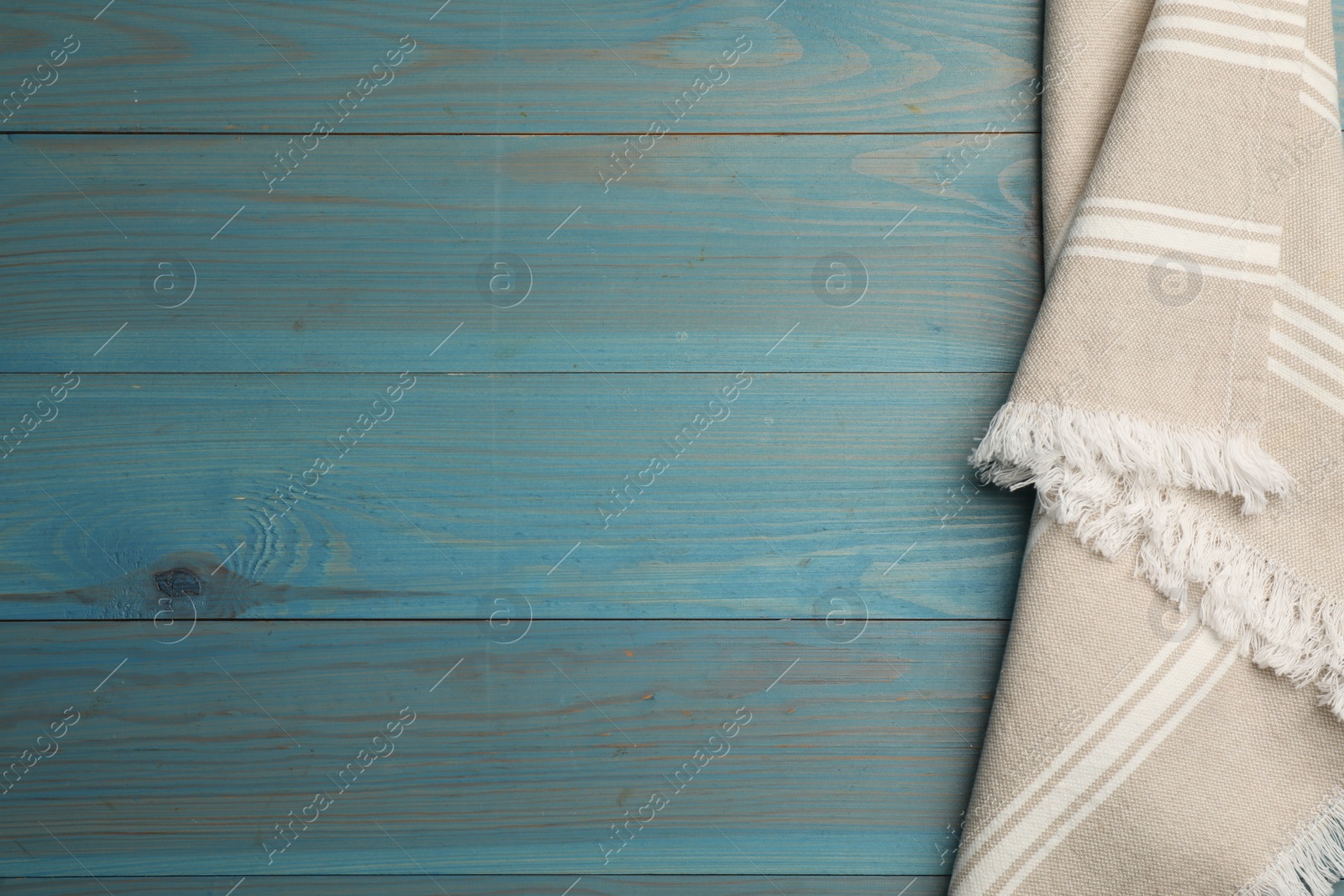 Photo of Striped kitchen towel on light blue wooden table, top view. Space for text