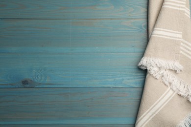 Striped kitchen towel on light blue wooden table, top view. Space for text